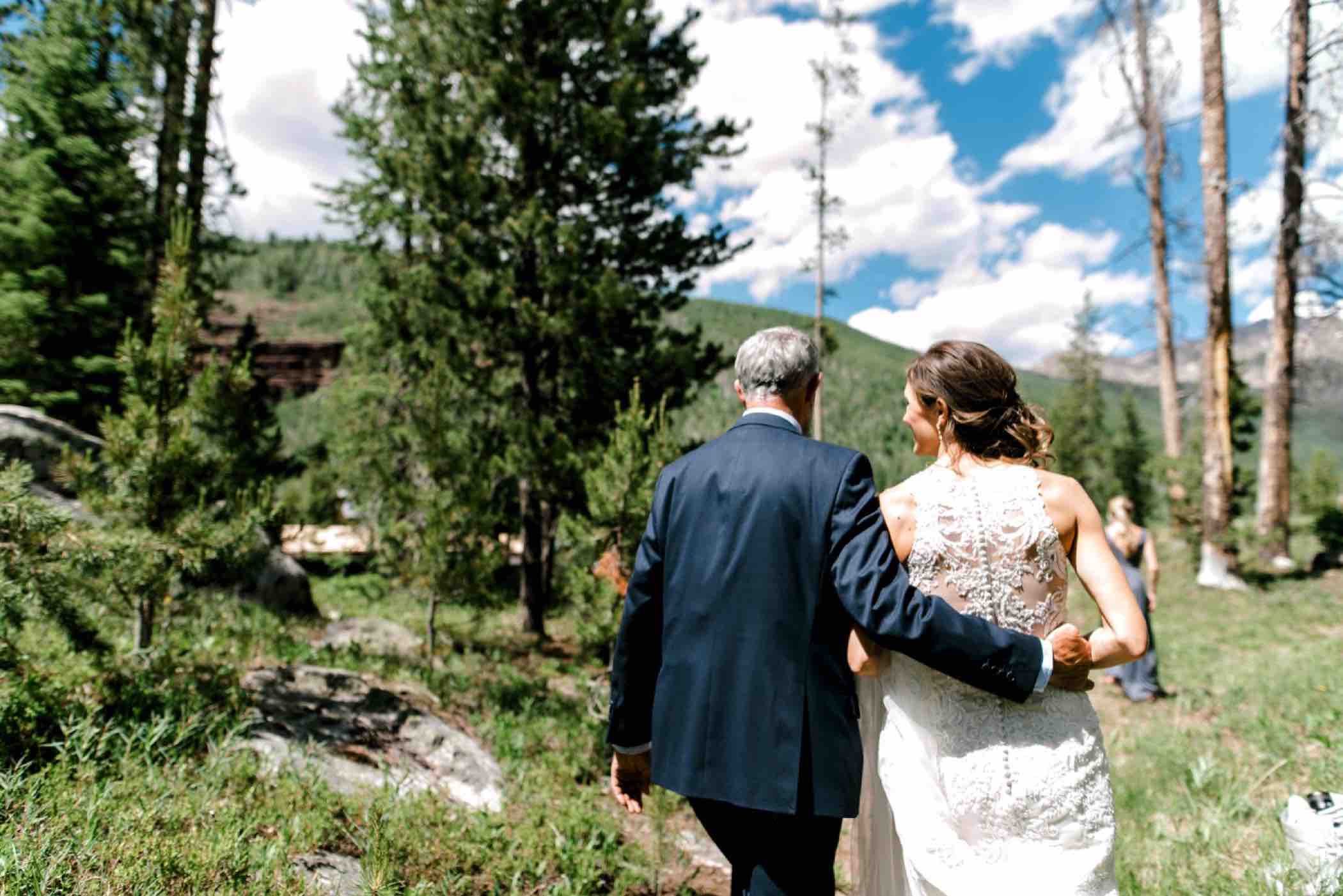 Sallie, the bride, and her father walk through the Vail pine forest outside Piney River Ranch. Photo by Ali and Garrett, Romantic, Adventurous, Nostalgic Wedding Photographers.