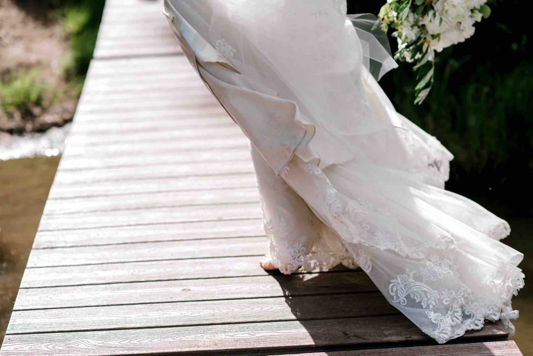 Bride's dress blows on the dock of the Piney Lake at Piney River Ranch in Vail, Colorado. Photo by Ali and Garrett, Romantic, Adventurous, Nostalgic Wedding Photographers.