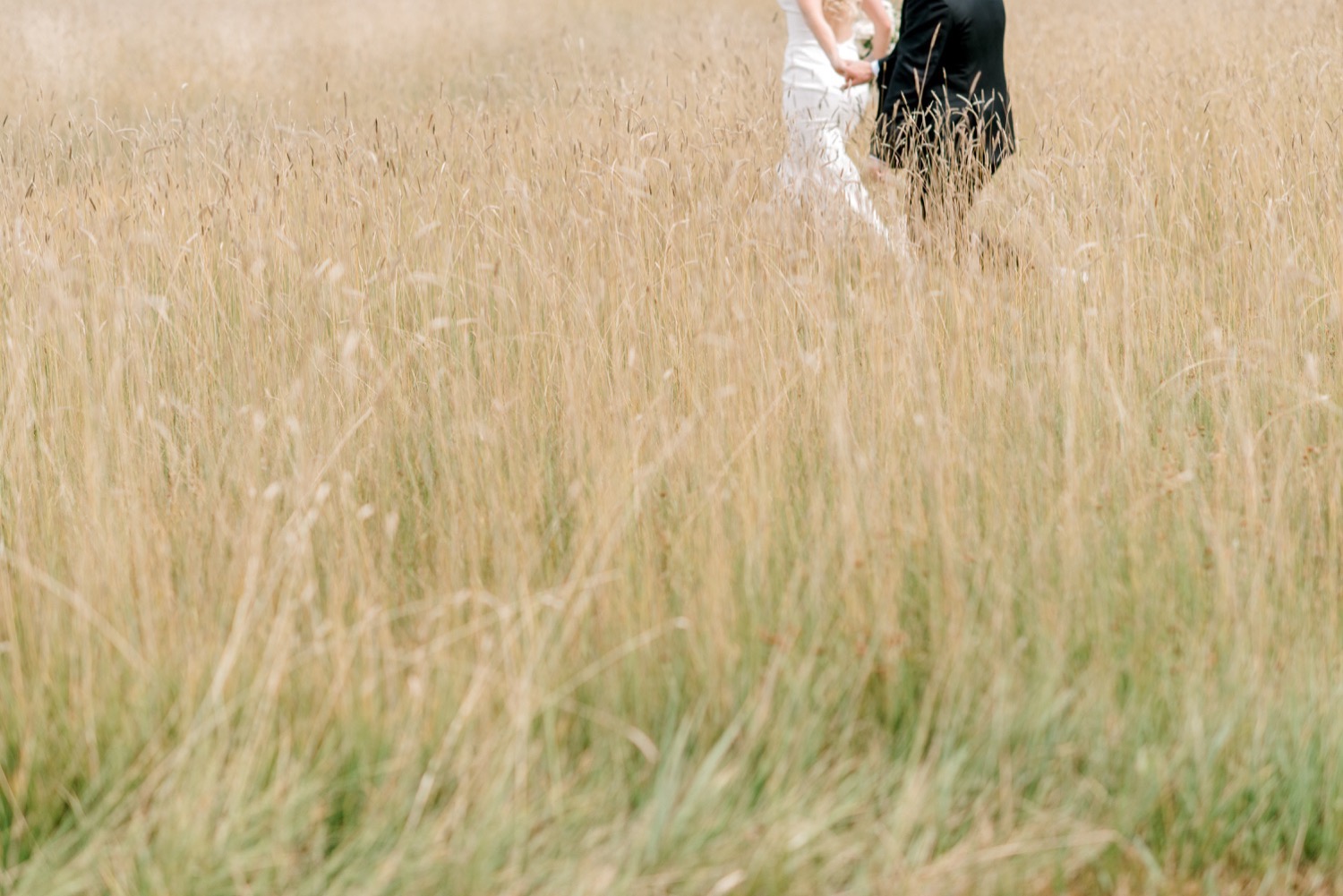 bride and groom running through field crested butte wedding