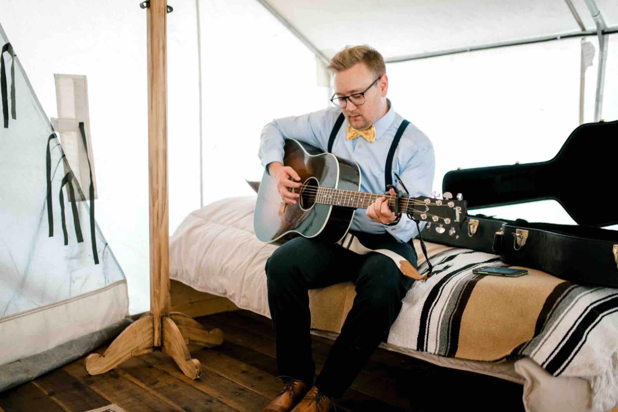 Kris' best friend plays music while the groomsmen get ready before his Piney River Ranch wedding in Vail, Colorado. Photo by Ali and Garrett, Romantic, Adventurous, Nostalgic Wedding Photographers.