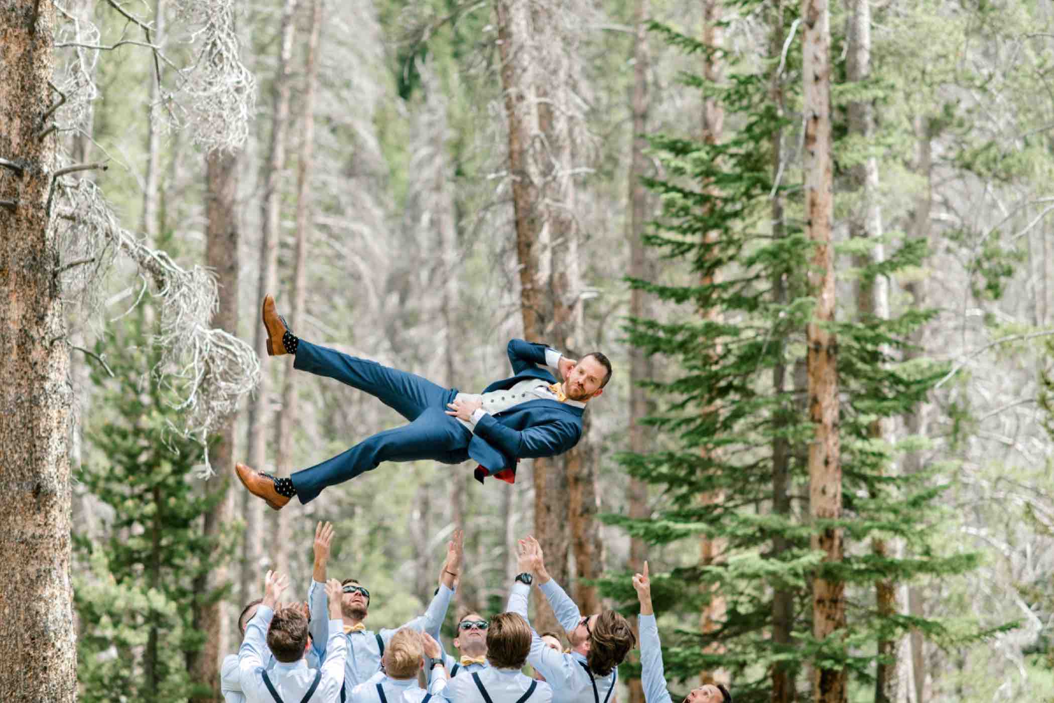 Groomsmen throwing the groom during photos outside Piney River Ranch in Vail in the Colorado Rocky Mountains. Photo by Ali and Garrett, Romantic, Adventurous, Nostalgic Wedding Photographers.