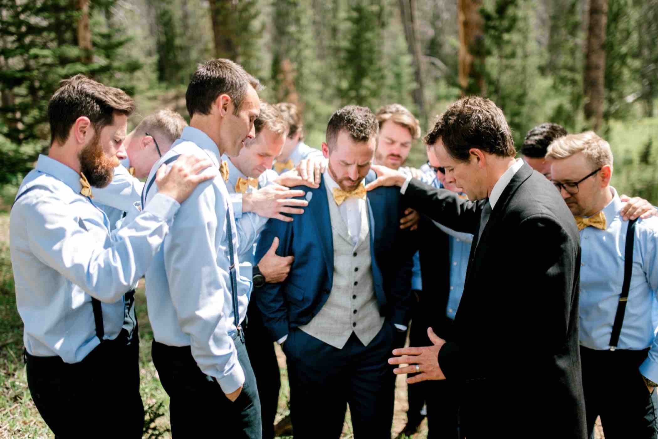 Groomsmen pray over the groom outside Piney River Ranch in Vail in the Colorado Rocky Mountains. Photo by Ali and Garrett, Romantic, Adventurous, Nostalgic Wedding Photographers.