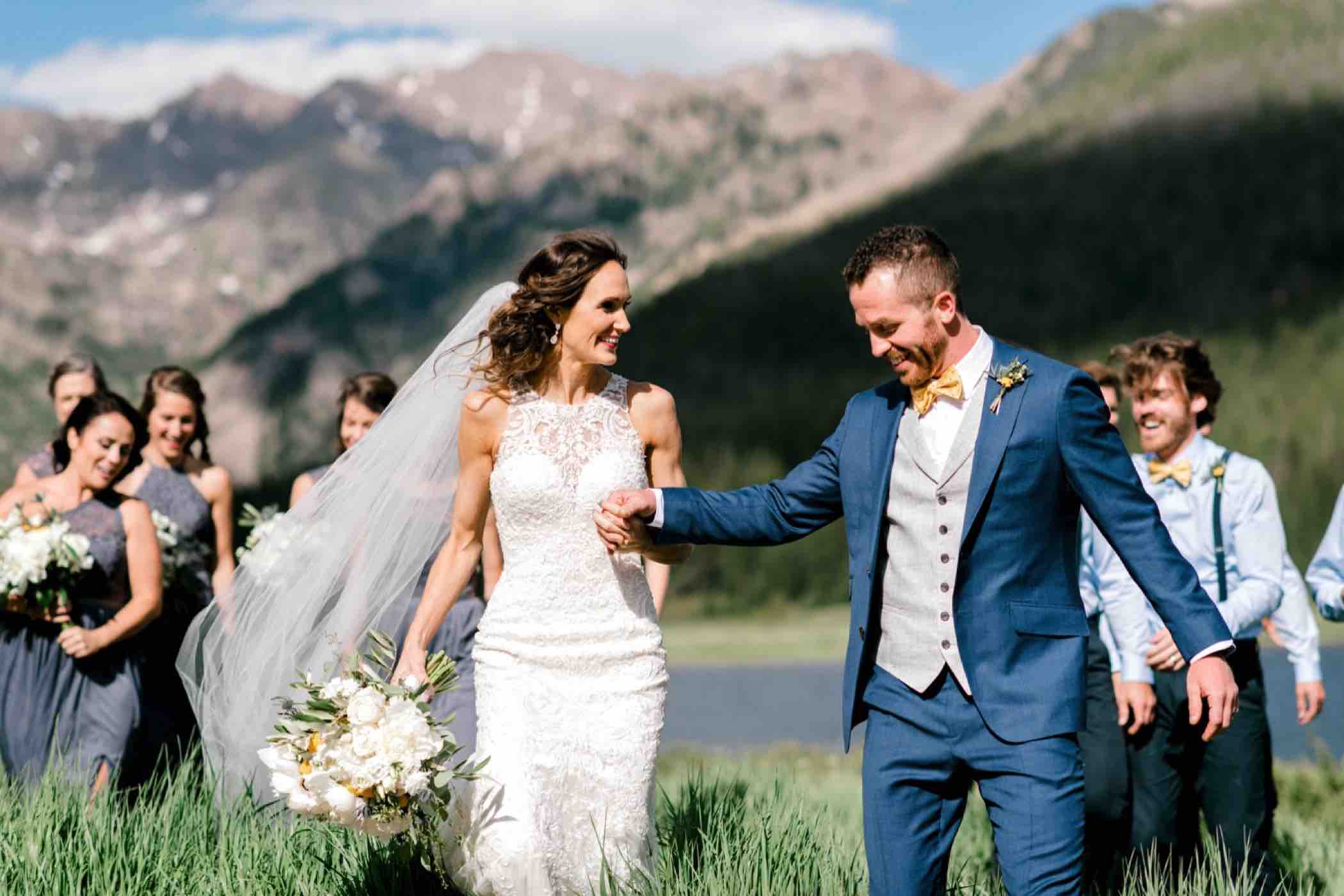 Bride and groom walk through the tall grass surrounded by their wedding party at Piney River Ranch in Vail, Colorado. Photo by Ali and Garrett, Romantic, Adventurous, Nostalgic Wedding Photographers.