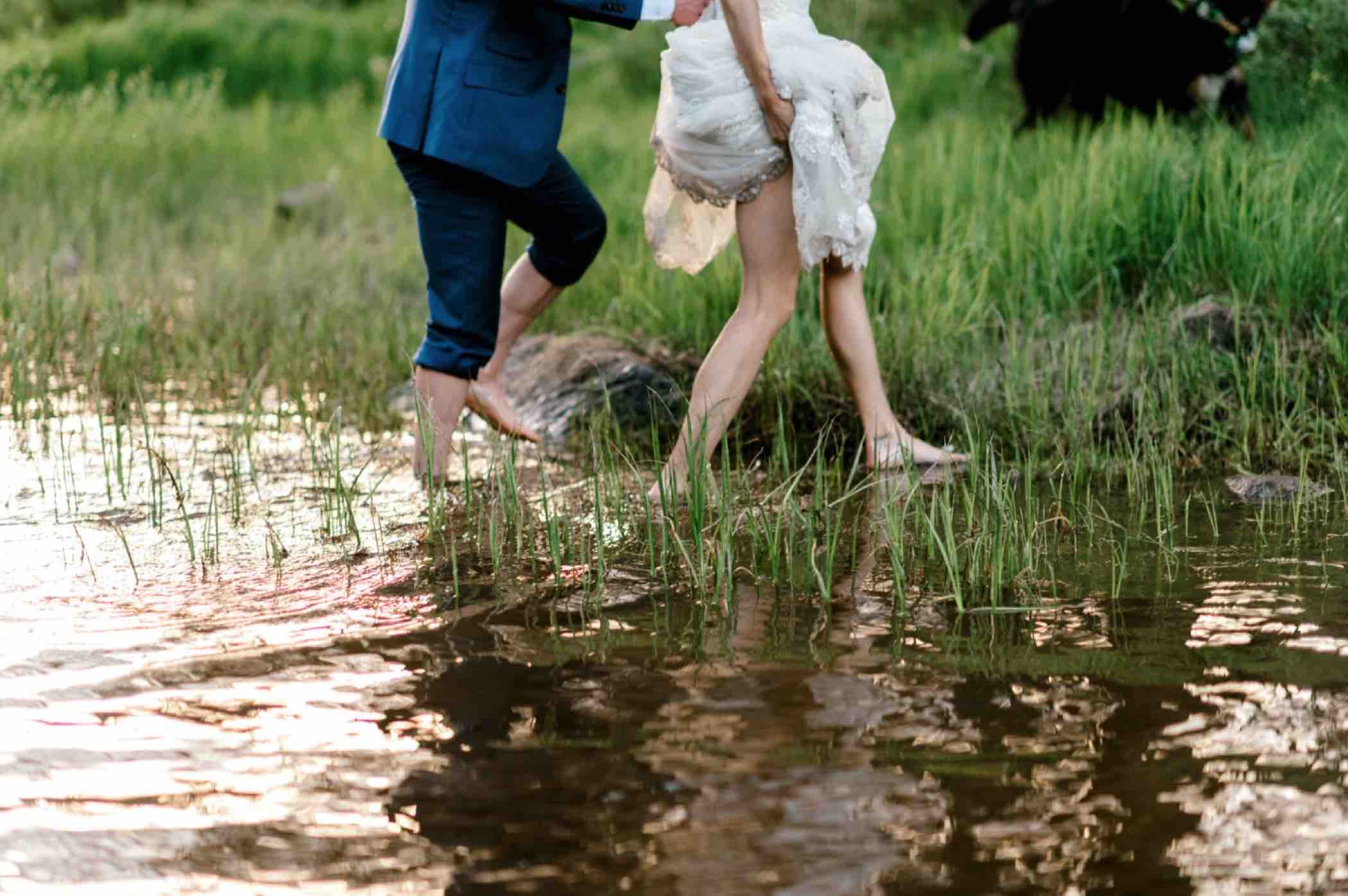 Kris and Sallie walk through Piney Lake for their bride and groom portraits after their wedding at Piney River Ranch in Vail, Colorado. Photo by Ali and Garrett, Romantic, Adventurous, Nostalgic Wedding Photographers.