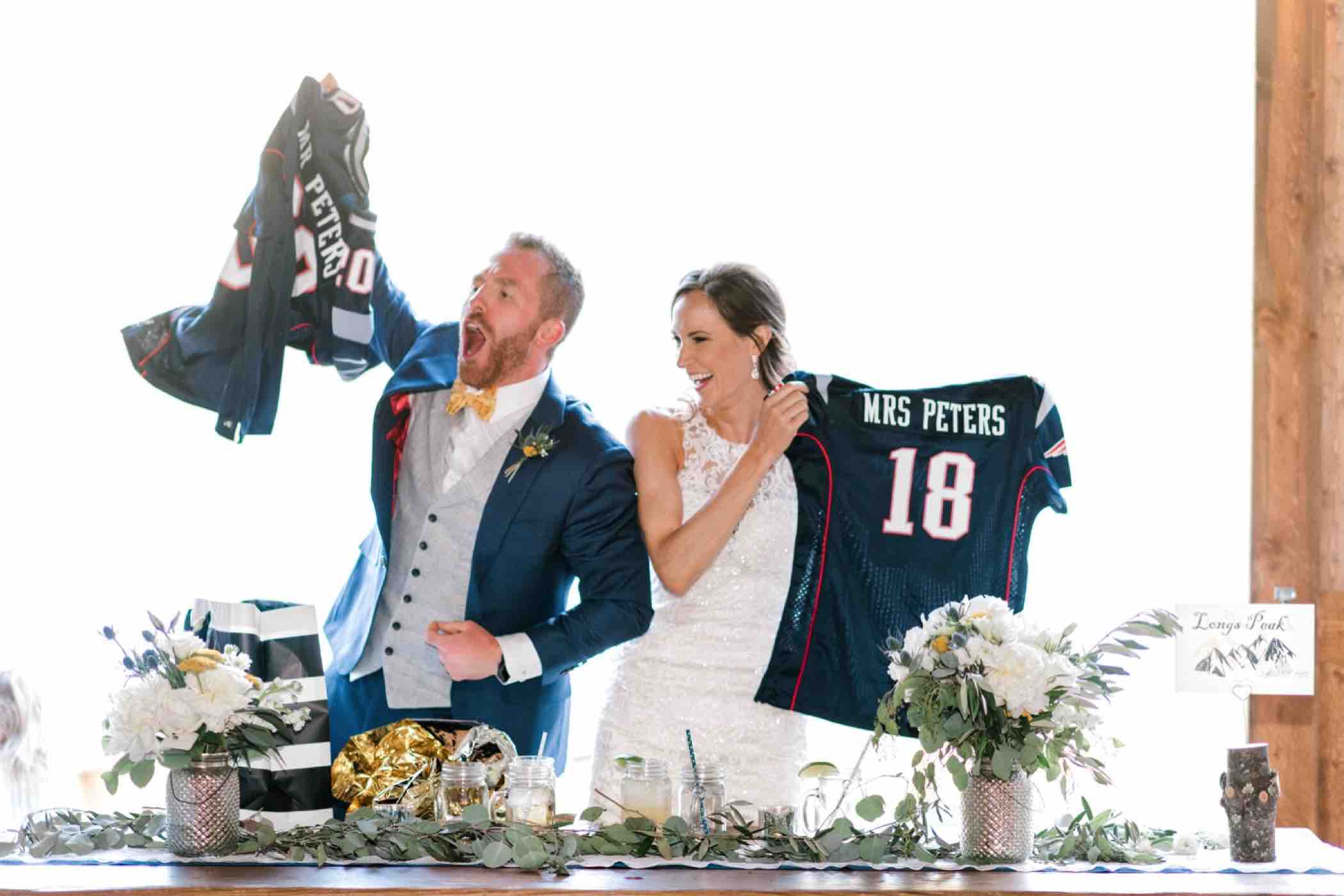 Bride and groom celebrate matching Patriot jersey gifts for their wedding at Piney River Ranch in Vail, Colorado. Photo by Ali and Garrett, Romantic, Adventurous, Nostalgic Wedding Photographers.