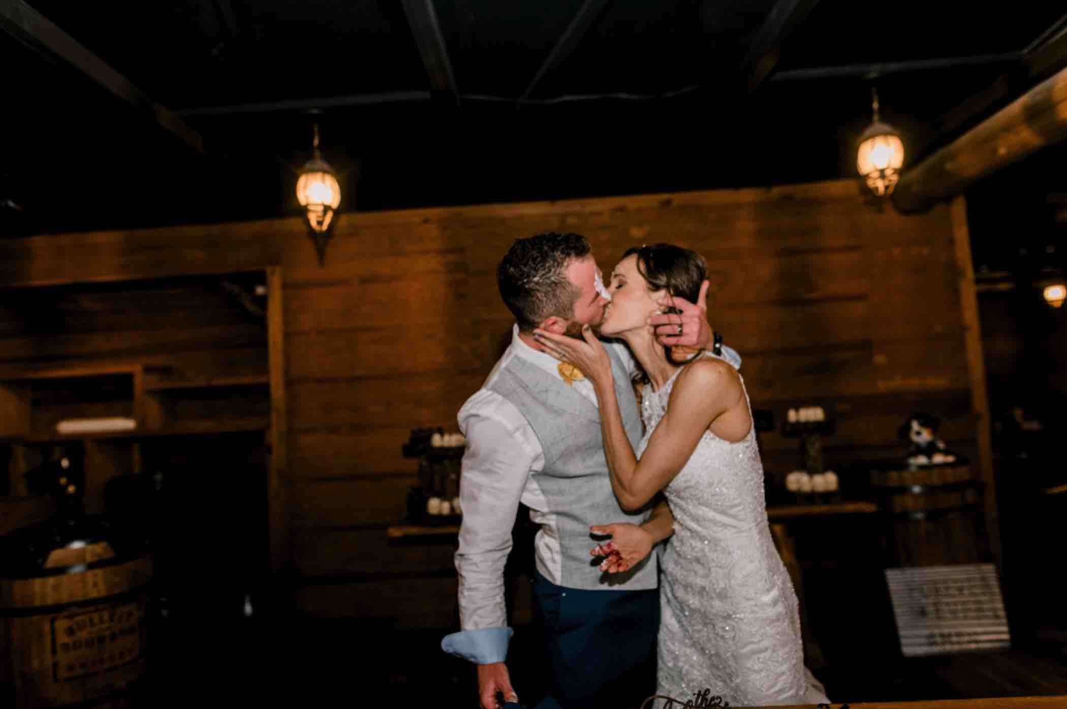 After smashing cake in each other's faces, the bride and groom share a kiss after cutting the cake at their wedding reception at Piney River Ranch in Vail, Colorado. Photo by Ali and Garrett, Romantic, Adventurous, Nostalgic Wedding Photographers.